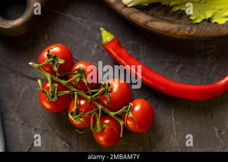 Delicious ripe cherry tomatoes, chili peppers and garlic for cooking  Stock Photo