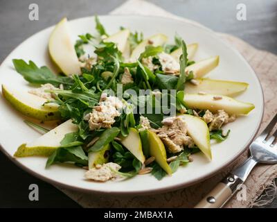 Plate with a pear and arugula salad with home made vegan feta cheese. Stock Photo