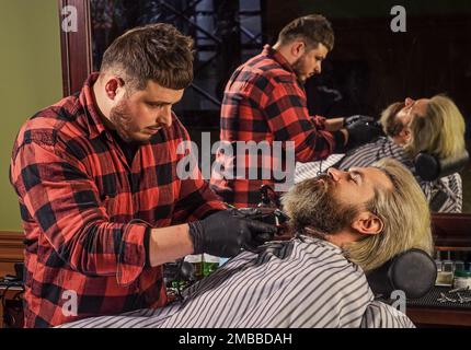 Making hair look magical. male beauty and fashion. mature man at barbershop. brutal bearded man at hairdresser. barber with male client. hipster with Stock Photo