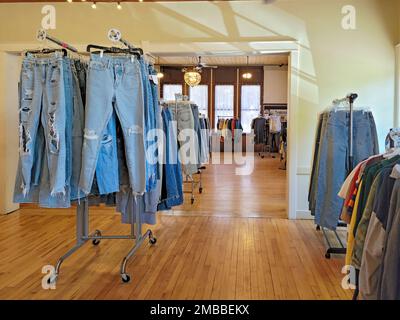 Distressed fashion denim blue jeans hanging on clothing racks in a store Stock Photo