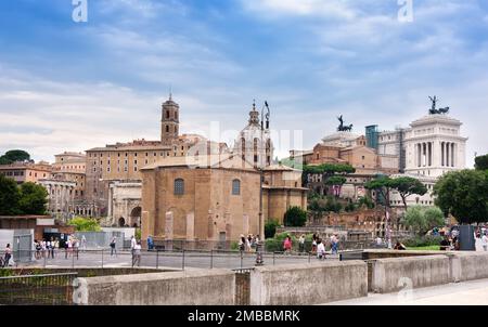 Rome, Italy - June 10, 2016:  Pedestrians observing the ancient ruins of the once Roman Forum, surrounded by other ancient governmental buildings. Stock Photo