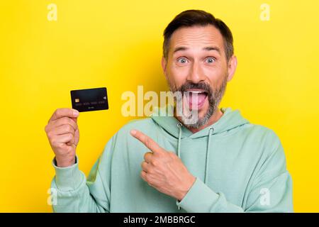 Close up photo of bearded overjoyed astonished man rejoice have bank plastic card offer proposition isolated on yellow color background Stock Photo