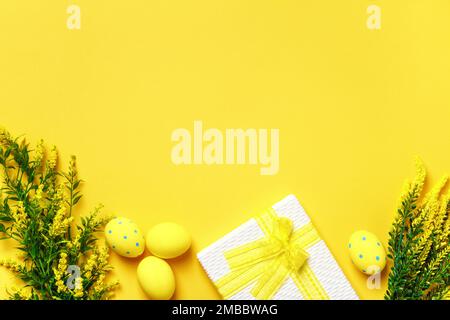 Easter composition. Eggs blossoming branch box with a gift on a yellow background. Copy space border. Stock Photo