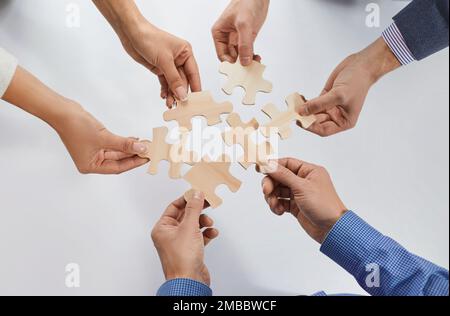 Hands of group of business people assembling jigsaw puzzle. cooperation, teamwork support concept. Stock Photo