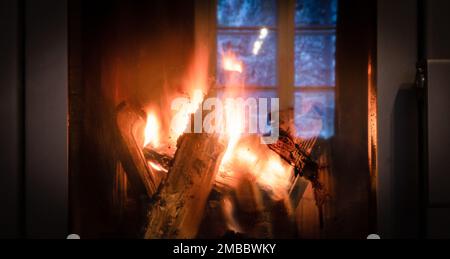 Fire in the fireplace behind a closed glass door. Stock Photo