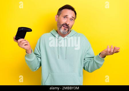 Portrait of worried man raise hand no answer cant complete game level isolated on yellow color background Stock Photo