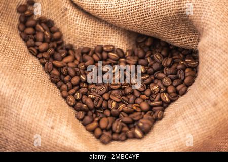 Roasted brown coffee beans or seeds in a jute sack, close up Stock Photo