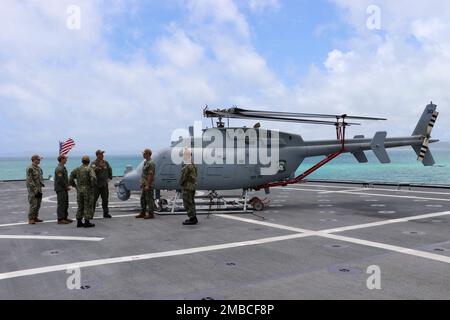 220614-N-EU544-0083 WHITE BEACH, Okinawa (June 14, 2022) Lt. Cmdr. Patrick Norwood, from Spring, Texas, middle, provides a brief about an MQ-8C Fire Scout, assigned to Helicopter Sea Combat Squadron 23, to Rear Adm. Derek Trinque, commander, Expeditionary Strike Group 7/Task Force 76, second from right, on the flight deck of the Independence-variant littoral combat ship USS Jackson (LCS 6). Jackson, part of Destroyer Squadron (DESRON) 7, is on a rotational deployment, operating in the U.S. 7th Fleet area of operations to enhance interoperability with partners and serve as a ready-response forc Stock Photo