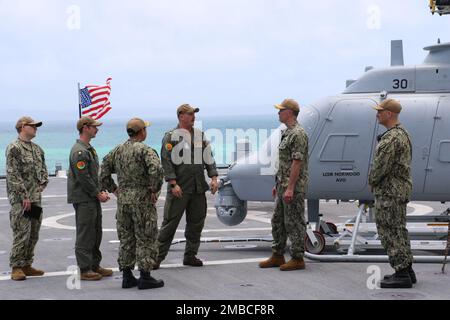 220614-N-EU544-0085 WHITE BEACH, Okinawa (June 14, 2022) Lt. Cmdr. Patrick Norwood, from Spring, Texas, center, provides a brief about an MQ-8C Fire Scout, assigned to Helicopter Sea Combat Squadron 23, to Rear Adm. Derek Trinque, commander, Expeditionary Strike Group 7/Task Force 76, second from right, on the flight deck of the Independence-variant littoral combat ship USS Jackson (LCS 6). Jackson, part of Destroyer Squadron (DESRON) 7, is on a rotational deployment, operating in the U.S. 7th Fleet area of operations to enhance interoperability with partners and serve as a ready-response forc Stock Photo