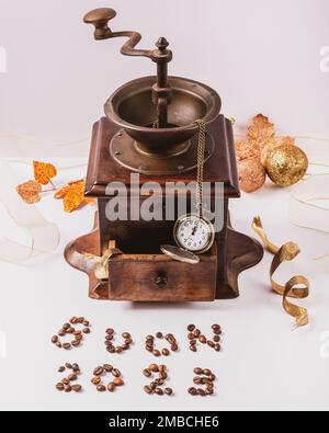 Coffee beans make up the inscription Buon 2023 which in Italian means happy 2023, with an antique wooden coffee grinder and a pocket watch in the back Stock Photo