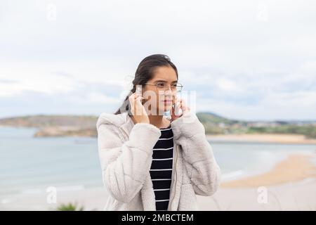 Hispanic lady with smartphone listening to music in wireless earphones Stock Photo