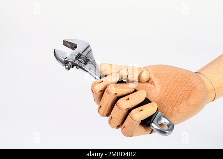 Wooden hand holding an adjustable spanner wrench Stock Photo