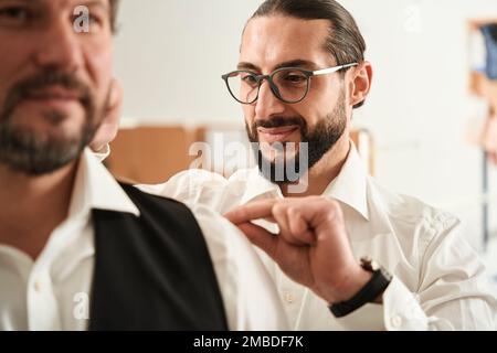 Pleased young fashion designer measuring male client Stock Photo