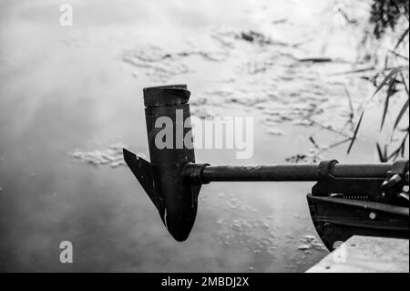 Boat trolling outboard motor extended over mossy water Stock Photo