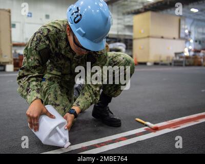 220615-N-IW069-1118 SAN DIEGO (June 15, 2022) Aviation Boatswain’s Mate (Handling) Airman Apprentice Valarie Tovar, a native of Guatemala, paints walkway lines in the hangar bay of Nimitz-class aircraft carrier USS Carl Vinson (CVN 70), June 15. Vinson is currently pierside in its homeport of San Diego. Stock Photo