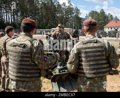 Staff Sgt. Dennis Yi, a U.S. Army Soldier assigned to Alpha Battery, 2nd Battalion, 146th Field Artillery Regiment, Washington Army National Guard, holds a howitzer familiarization class for British and Romanian soldiers at Bemowo Piskie Training Area, Bemowo Piske, Poland, June 15, 2022. Stock Photo