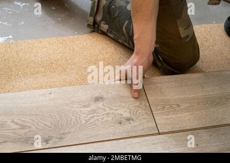 A man lays a laminate floor. Repair in the apartment. Laminate floor professionally installed. Stock Photo