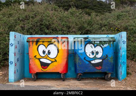 Two waste wheelie bins with graffiti cartoon faces painted on them Stock Photo