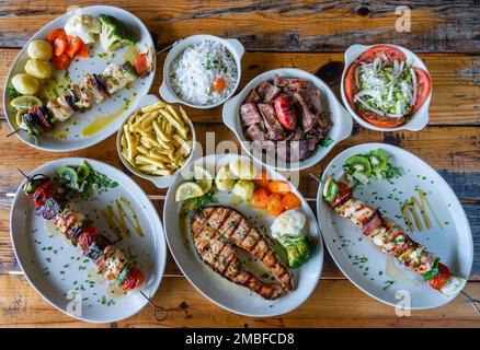 Skewer mixed grilled meat on plate with vegetables salad rice potato cusida. traditional food. Skewer fish Stock Photo