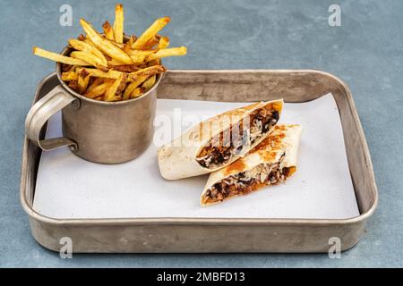 Wrap a pork chicken burrito with spices and fries in a mug. Stock Photo