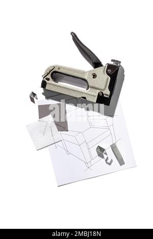 Silver furniture stapler gun with staples and the drawing of the armchair isolated on white background. Manual industrial tool Stock Photo