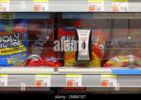 Candy on a locked store shelf with a wireless customer service call button requesting help unlocking said items at a Walgreens drugstore. Stock Photo