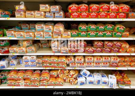 Different varieties of mass produced white bread on an American supermarket grocery store shelf. Stock Photo