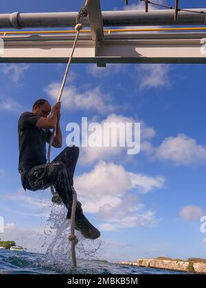 A Dutch Marine with Marine Squadron Carib, Netherlands Marine Corps, climbs a rope during Exercise Caribbean Coastal Warrior at Savaneta, Aruba, June 16, 2022. This bilateral training exercise allows 2d Reconnaissance Battalion, 2d Marine Division, to expand its knowledge and proficiency when operating in littoral and coastal regions. Caribbean Coastal Warrior continues to increase global interoperability between the U.S. Marines and the Dutch Marines as well as Caribbean Urban Warrior, an annual training evolution conducted on Camp Lejeune, North Carolina. Stock Photo