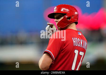 Philadelphia Phillies - Rhys Hoskins, wearing the cream Phillies uniform,  celebrating with the dugout after scoring a run.