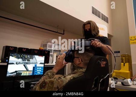 U.S. Air Force Tech. Sgt. Levi Reynolds, left, 60th Air Mobility Wing public affairs noncommissioned officer in charge of command information, puts on a virtual reality headset during a phoenix spark industry day at Travis Air Force Base, California, June 17, 2022. The virtual reality headset and system simulated air refueling operations. The event hosted external companies to pitch ideas to the base population through presentations and was designed to bring the latest technology from the private sector and bring it to Team Travis to develop new ways to win the next fight. Stock Photo