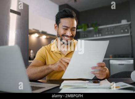 Planning, smile and Asian man with paperwork and a laptop for finance budget, entrepreneurship and tax. Happy, summary and freelancer reading the Stock Photo
