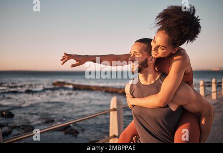 Fitness, couple and piggyback for beach sunset, travel or fun holiday journey together in the outdoors. Happy man and woman enjoying back ride by the Stock Photo