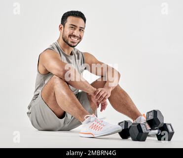 Be the hardest working person in whatever you do. Studio portrait of a muscular young man posing with dumbbells against a white background. Stock Photo