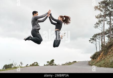 We finally overcame our biggest challenge. Full length shot of two young athletes jumping for joy after their morning run outdoors. Stock Photo
