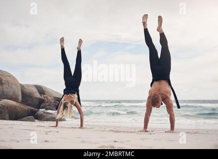 Changing your perspective, changes your experience. a couple doing handstands on the beach. Stock Photo