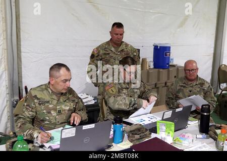Lt. Col. Andrew O’Connor (right) and Maj. Mike Adams (standing), members of a 28th Infantry Division senior trainer team, review personnel tracking procedures with Capt. Shawn Updegrove (left) and Lt. Col. Alicia Partin, both with the 213th Regional Support Group, June 21, 2022 at the National Training Center, Fort Irwin, Calif. Partin and Updgrove served as the mayor and assistant mayor, respectively, of the 213th’s white cell established at Fort Irwin in support of the 56th Stryker Brigade Combat Team’s NTC rotation. Stock Photo