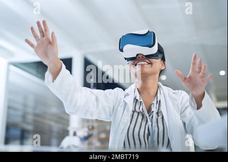 We cant change everything but we can change how we see it. a young scientist using a virtual reality headset while conducting research in a laboratory Stock Photo