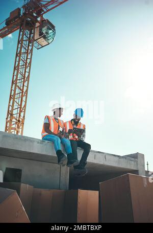 Canteens look a bit different when you work in construction. a young man and woman using a digital tablet on top of a building at a construction site. Stock Photo