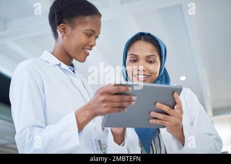 The best gadget in a scientists toolkit. two young scientists using a digital tablet in a laboratory. Stock Photo
