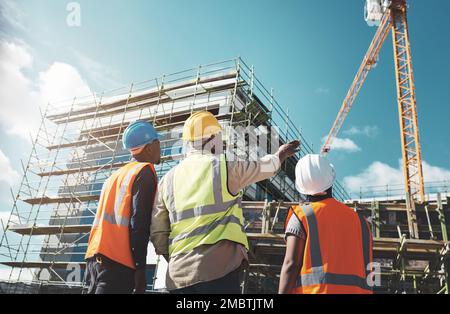 Teamwork is the key ingredient in quality construction. a group of builders assessing progress at a construction site. Stock Photo