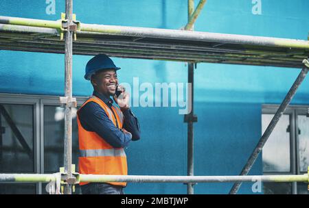 Setting a solid foundation for a strong superstructure. a young man talking on a cellphone while working at a construction site. Stock Photo