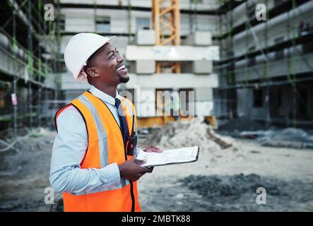 It takes foresight to manage an effective job site. a young man going over building plans at a construction site. Stock Photo