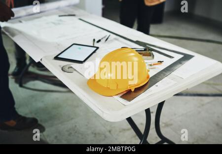 Safety is always part of the plan. various tools and a blueprint on a table at a construction site. Stock Photo