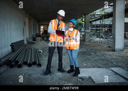 Set targets then set out to achieve them. a young man and woman having a discussion while working at a construction site. Stock Photo