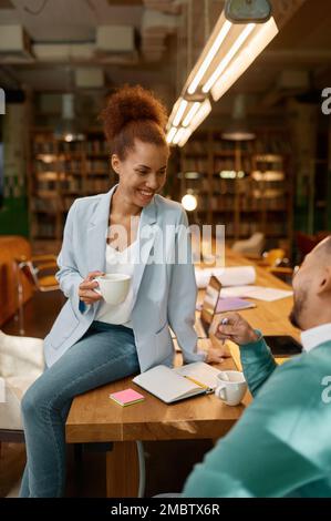 Positive female and male laughing during nice conversation in coworking space Stock Photo