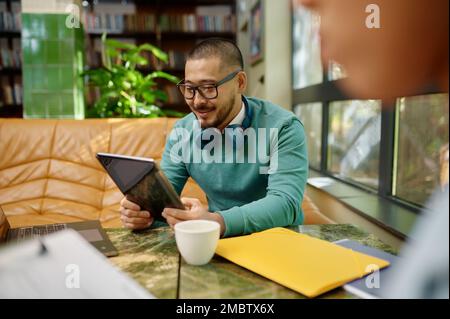 Young smiling employee using digital tablet screen coworking space Stock Photo