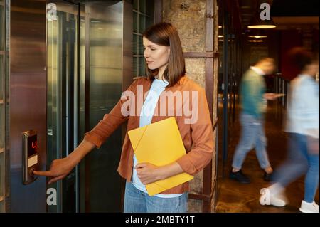 Business woman using elevator in hall of coworking office Stock Photo