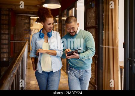 Diverse colleagues talking in hallway of modern coworking office Stock Photo
