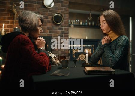 Old gypsy fortune teller and young woman performing magic ritual Stock Photo