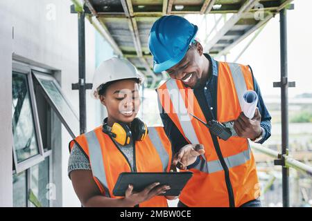 Successful project managers must be highly organised and detailed. a young man and woman using a digital tablet while working at a construction site. Stock Photo